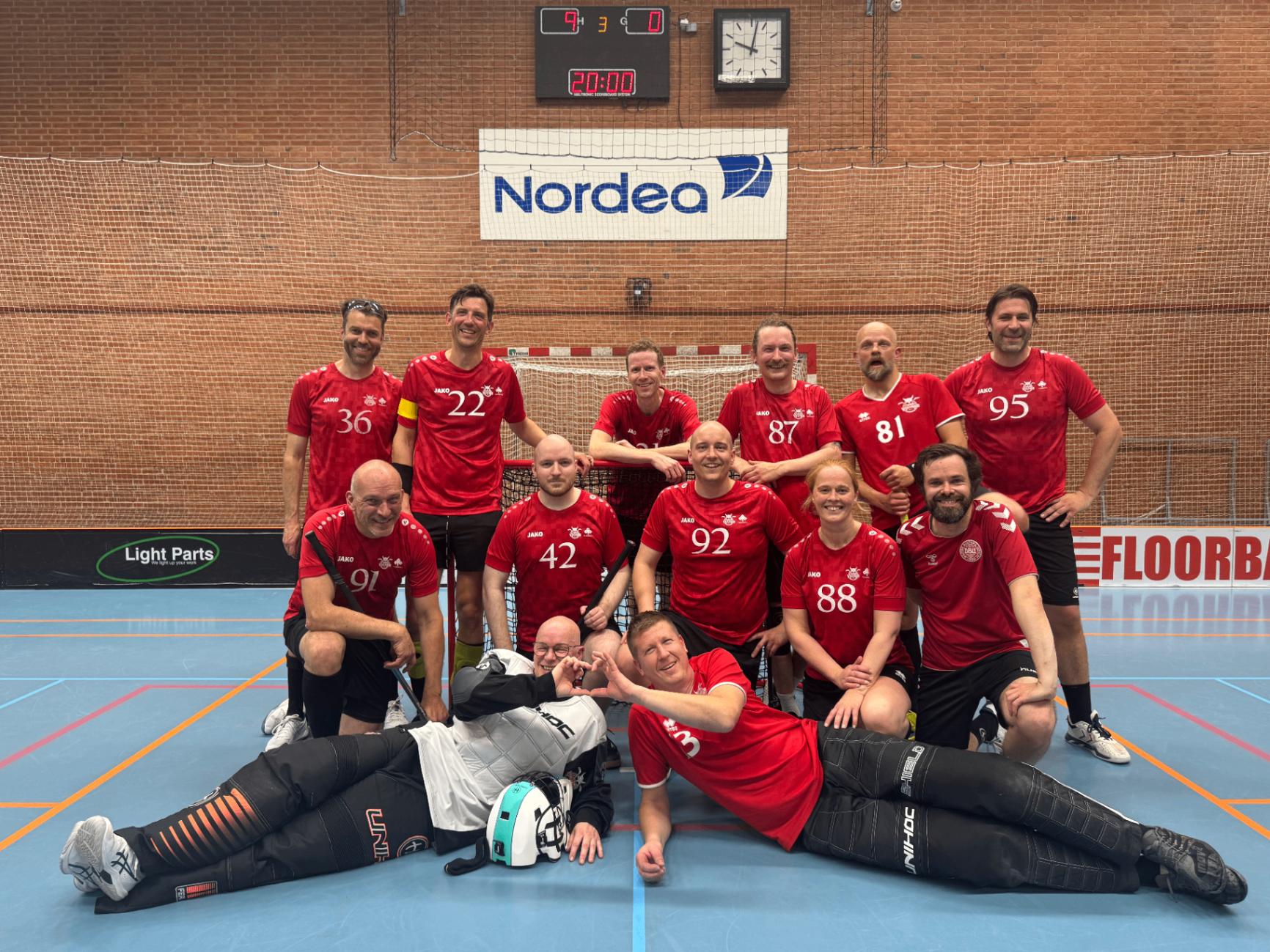 Voksenhold hos Lystrup Vikings Floorball poserer samlet i hallen efter kamp i røde spillertrøjer