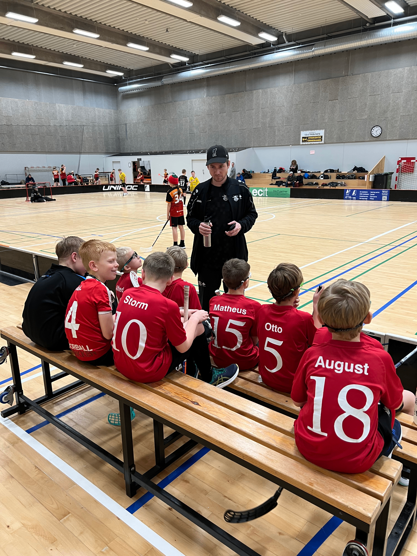 Lystrup Vikings ungdomshold sidder på bænken og får taktik af træneren under floorballturnering